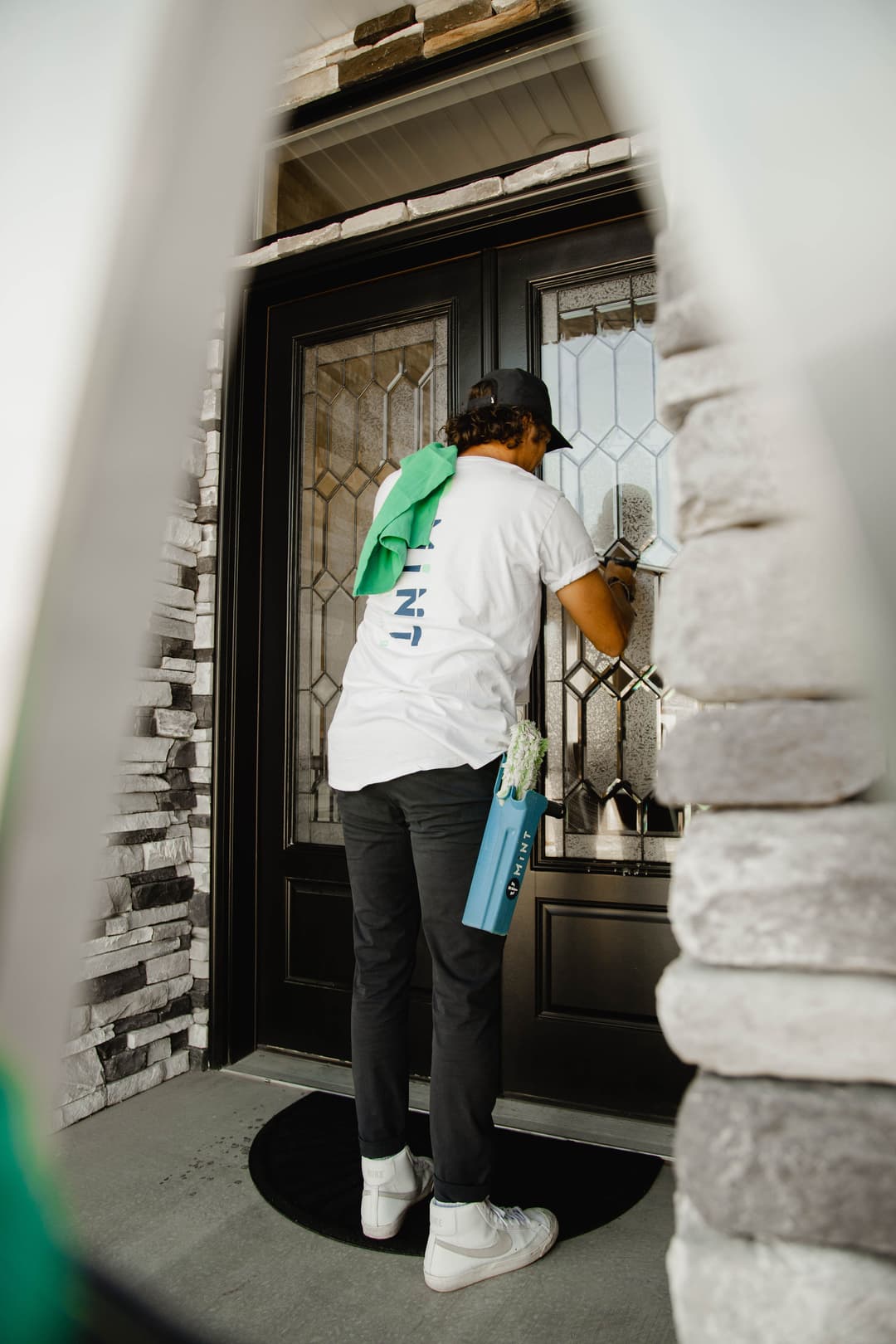 Person cleaning a front door with a towel and cleaning supplies, enhancing home appearance.