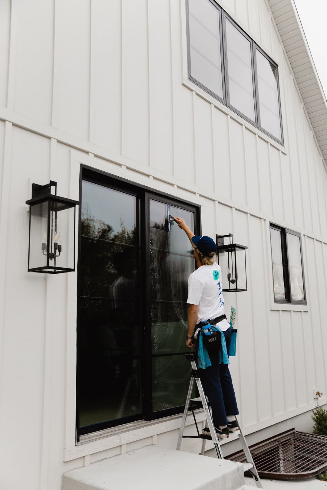 Professional window cleaner using a squeegee on modern home exterior.
