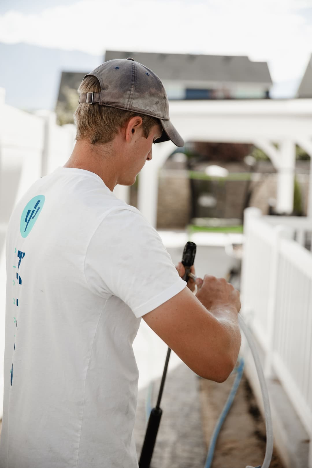 Young man operating a pressure washer outdoors, focused on cleaning a pathway.