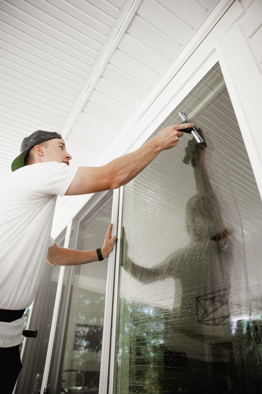 Man cleaning large window with a squeegee, showcasing effective window washing techniques.