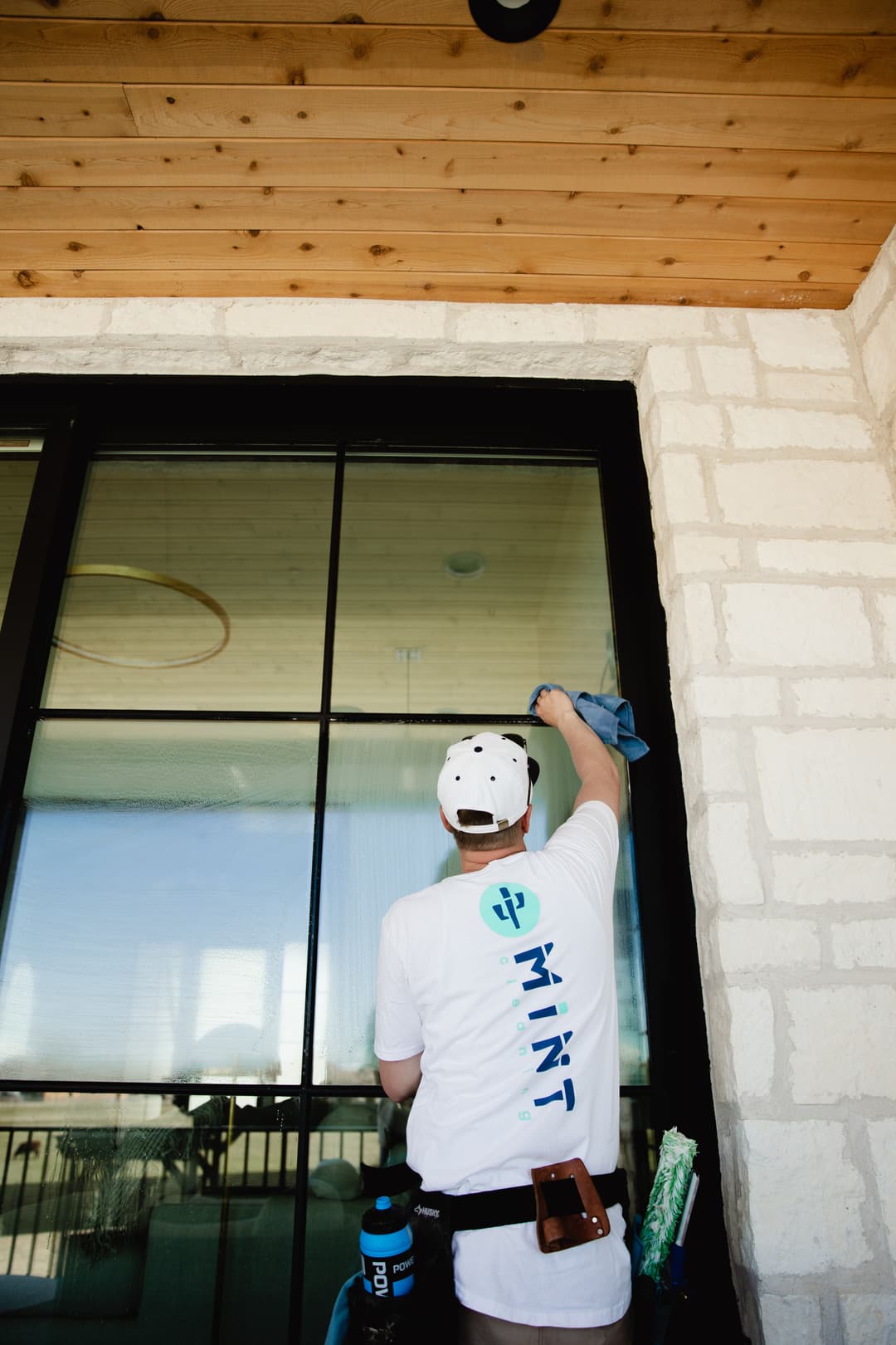 Window cleaning service by a professional in a branded shirt, focusing on glass surfaces.