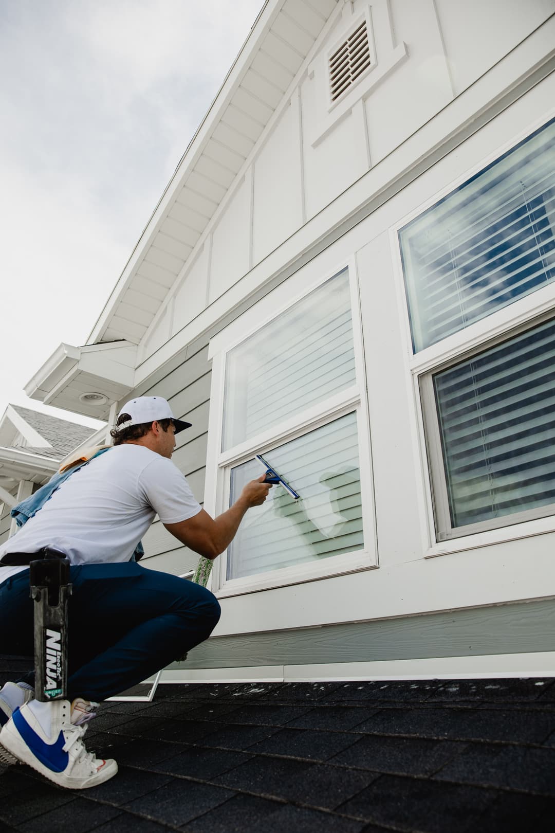 Window cleaning service performed by a professional on a residential house exterior.