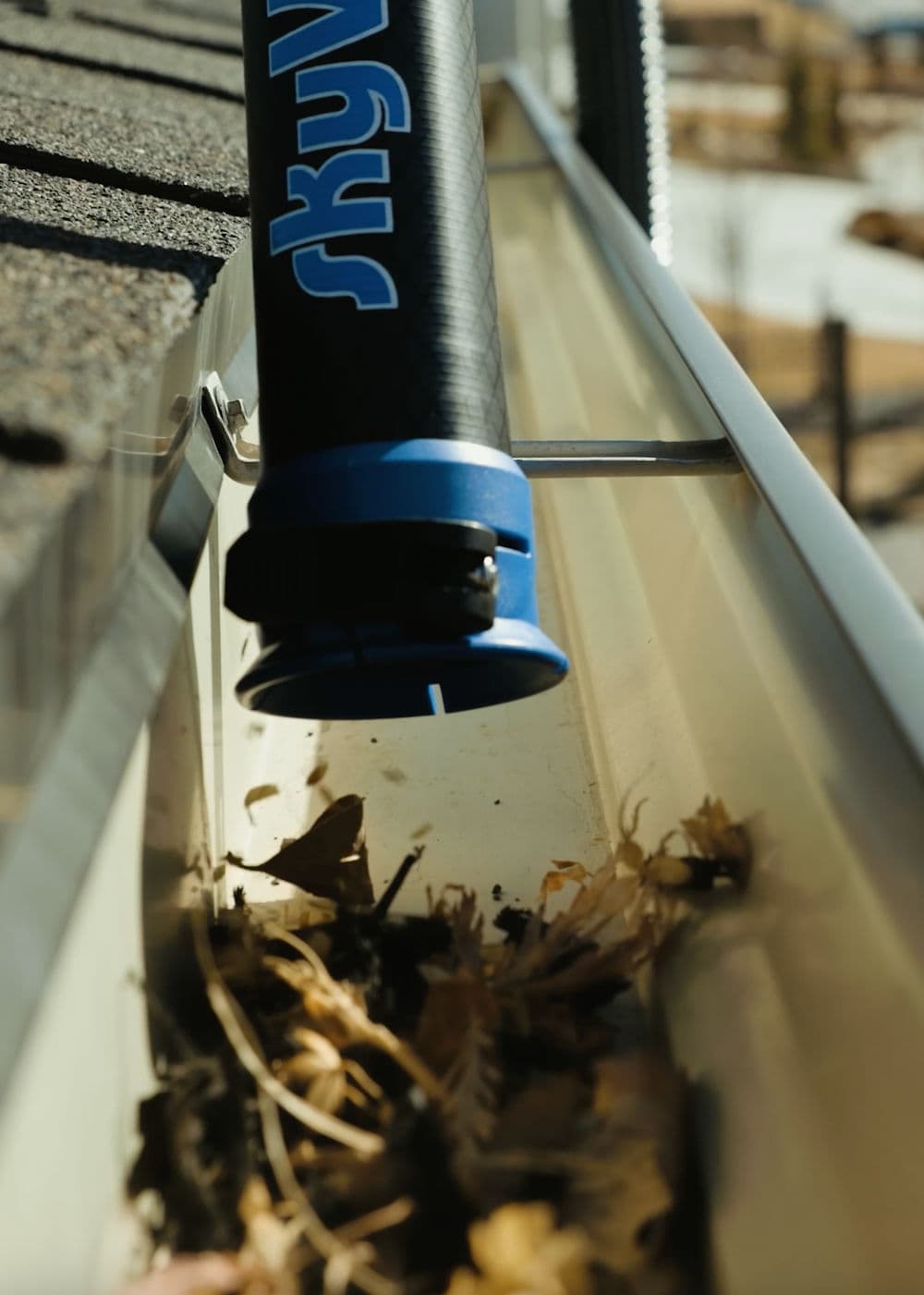 Gutter cleaning tool removing debris from a residential gutter system.