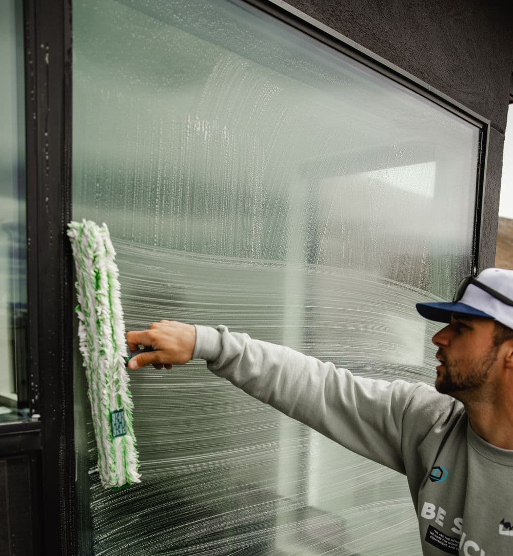 Man cleaning window with squeegee, showcasing professional window cleaning techniques.