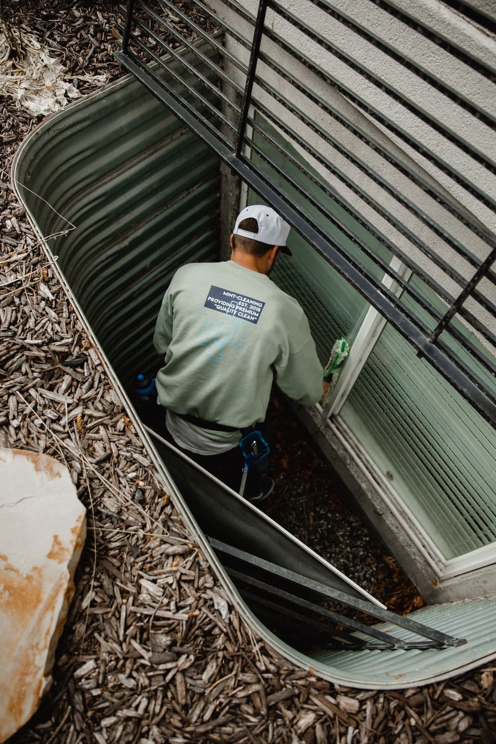 Maintenance worker inspecting a basement window with a focus on safety equipment.